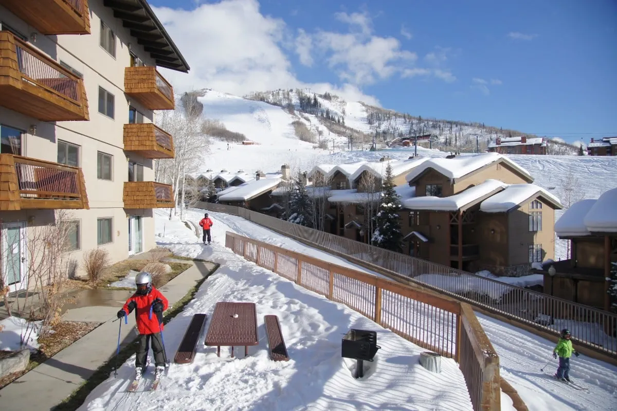This exterior scene spotlights a child skiing on a snow-covered mountain, with nearby buildings, benches, and a pathway. The environment is playful and active, highlighting family-friendly amenities and the seamless connection between the property and the village's recreational offerings.